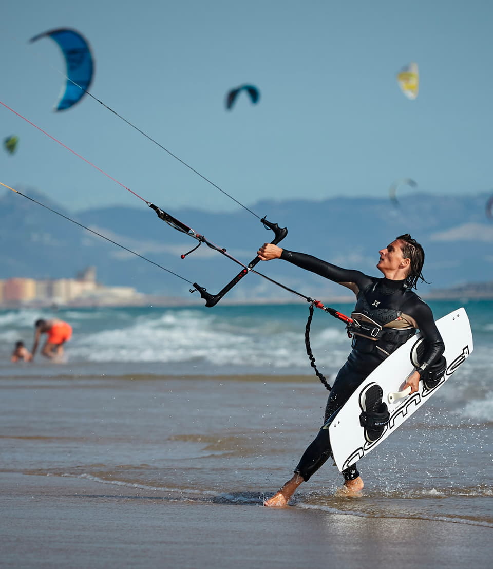 Kitesurfer saliendo del mar en Tarifa con la cometa y la tabla en la mano